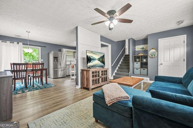 2959 Pritchards Mill Trl, Douglasville, GA 30135 - living room with a textured ceiling, a ceiling fan, wood finished floors, stairs, and baseboards
