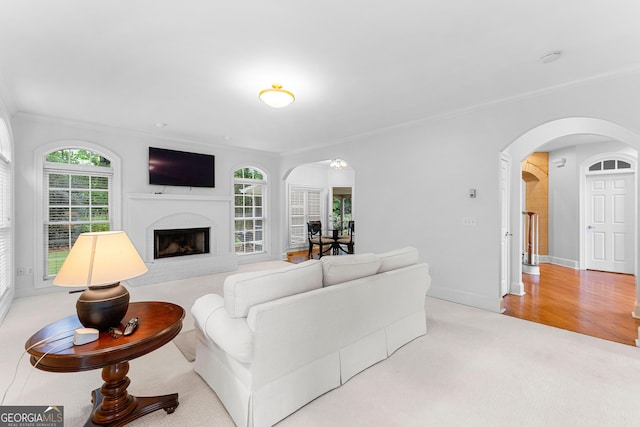 160 Torrey Pines Ct, Newnan, GA 30265 - living room featuring arched walkways, ornamental molding, a fireplace with raised hearth, carpet floors, and baseboards
