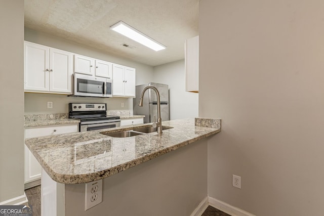 3151 Kingswood Gln, Decatur, GA 30034 - kitchen with appliances with stainless steel finishes, a sink, a peninsula, baseboards, and a textured ceiling