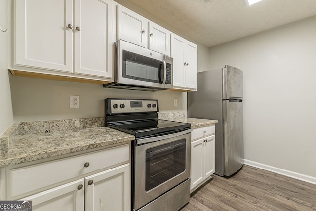 3151 Kingswood Gln, Decatur, GA 30034 - kitchen with stainless steel appliances, light wood-style flooring, white cabinets, baseboards, and light stone counters