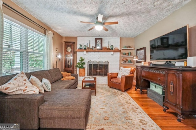 4442 Mclain Cir, Acworth, GA 30101 - living area featuring a fireplace, ceiling fan, light wood finished floors, and a textured ceiling
