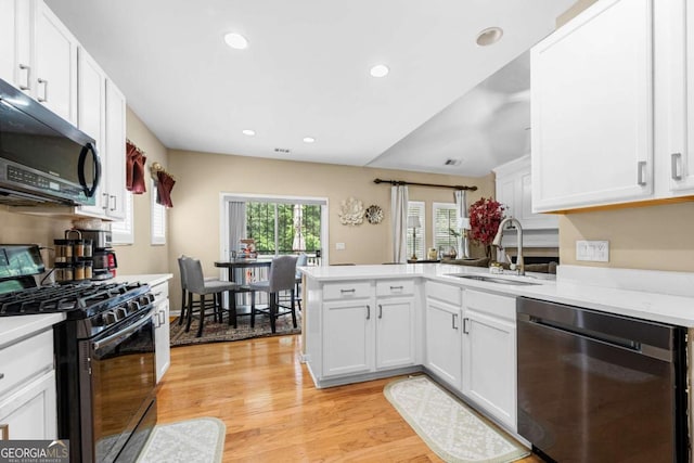 1536 Fenmore St, Lithia Springs, GA 30122 - kitchen featuring stainless steel dishwasher, black gas range, a peninsula, light countertops, and white cabinets