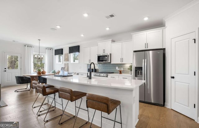 352 Foxglove Way, Mcdonough, GA 30253 - kitchen featuring stainless steel appliances, a center island with sink, light countertops, a kitchen bar, and white cabinetry