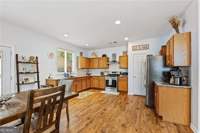 130 Nacoochee Way, Canton, GA 30114 - kitchen featuring stainless steel appliances, wall chimney exhaust hood, light wood finished floors, brown cabinetry, and recessed lighting