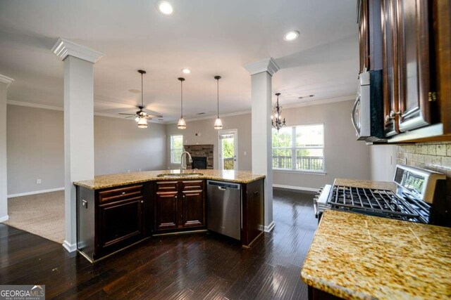 1021 Reddy Farm Rd, Grayson, GA 30017 - kitchen featuring a stone fireplace, stainless steel appliances, crown molding, a ceiling fan, and dark brown cabinetry