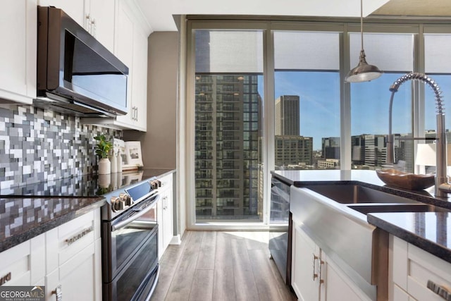 855 Peachtree St NE Unit 1703, Atlanta, GA 30308 - kitchen featuring stainless steel appliances, light wood-style floors, white cabinets, tasteful backsplash, and dark stone countertops