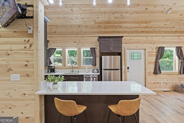 139 Maple Ridge Dr, Cleveland, GA 30528 - kitchen featuring stainless steel appliances, a sink, a breakfast bar area, light countertops, and wood walls