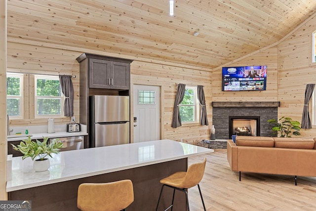139 Maple Ridge Dr, Cleveland, GA 30528 - kitchen featuring appliances with stainless steel finishes, a kitchen breakfast bar, light wood-style flooring, wood walls, and plenty of natural light