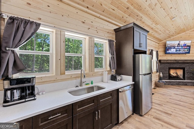 139 Maple Ridge Dr, Cleveland, GA 30528 - kitchen featuring stainless steel appliances, a sink, wooden walls, lofted ceiling, and dark brown cabinetry