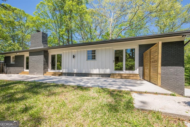 3350 Pine Meadow Rd NW, Atlanta, GA 30327 - rear view of house with entry steps, a chimney, brick siding, a lawn, and a patio area