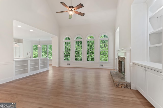 140 Longwater Cv, Roswell, GA 30075 - unfurnished living room featuring a stone fireplace, ceiling fan, high vaulted ceiling, light wood-type flooring, and a sink