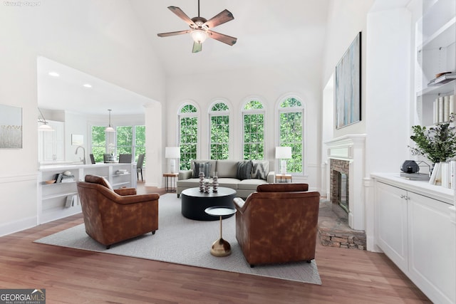 140 Longwater Cv, Roswell, GA 30075 - living area with high vaulted ceiling, ceiling fan, a glass covered fireplace, and light wood-type flooring