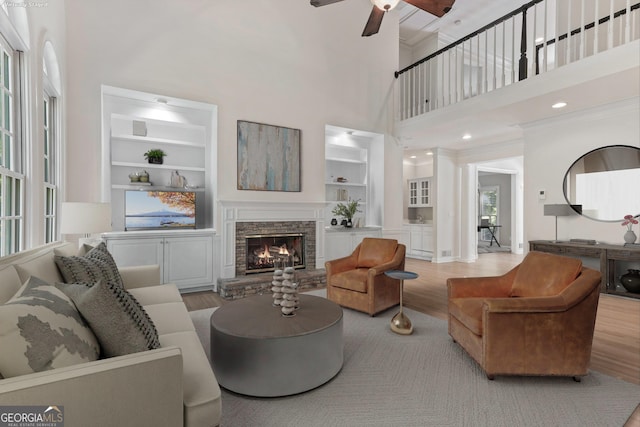 140 Longwater Cv, Roswell, GA 30075 - living room with a towering ceiling, light wood-style flooring, a ceiling fan, a fireplace, and built in features