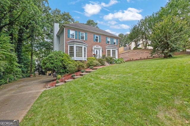 3897 Tanbark Ct, Marietta, GA 30066 - view of front facade with a chimney, a front lawn, concrete driveway, and brick siding