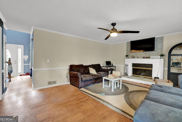 3897 Tanbark Ct, Marietta, GA 30066 - living room with a ceiling fan, wood finished floors, crown molding, a fireplace, and a textured ceiling