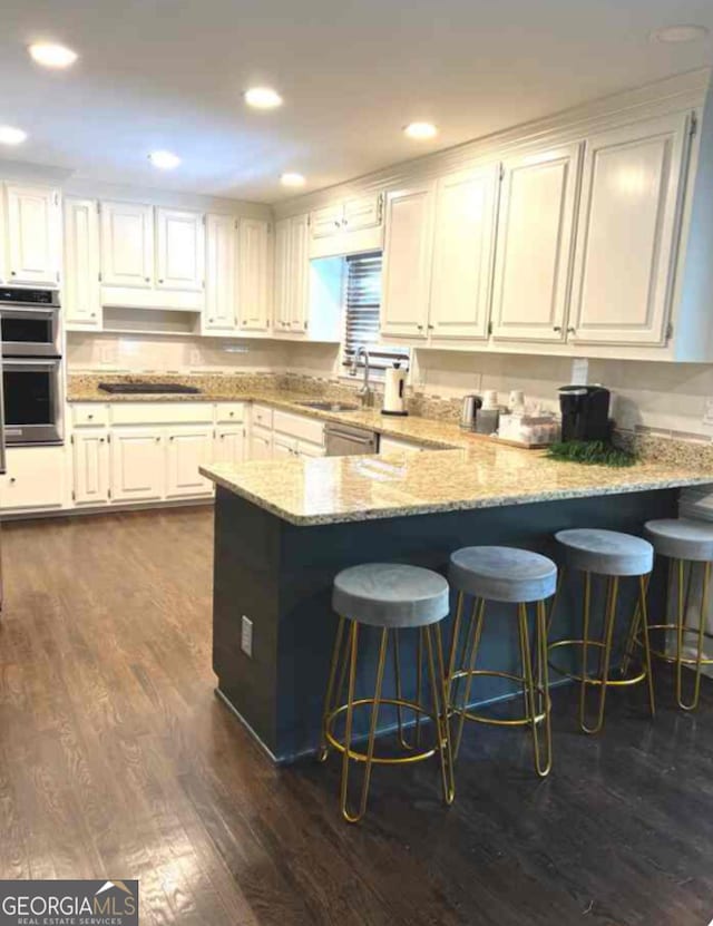 30 Highlands Ln, Oxford, GA 30054 - kitchen featuring double oven, a peninsula, dark wood-style flooring, light stone counters, and recessed lighting