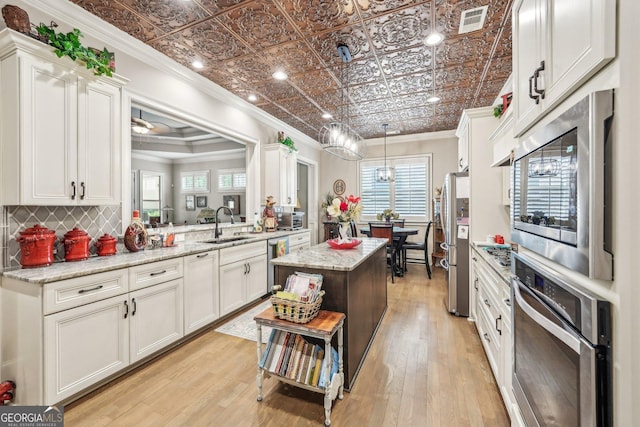 332 Rosshandler Rd, Suwanee, GA 30024 - kitchen with appliances with stainless steel finishes, ornamental molding, a sink, a kitchen island, and white cabinetry
