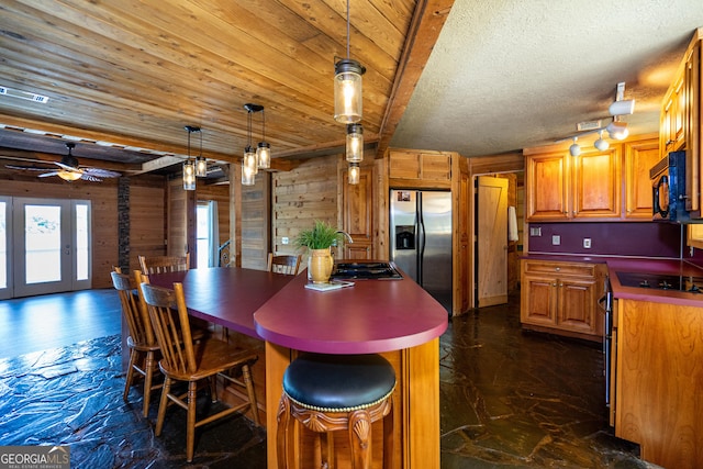230 Kelly Dr, Hamilton, GA 31811 - kitchen with stainless steel fridge with ice dispenser, wood walls, a center island, a sink, and brown cabinetry