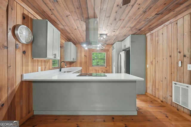853 Bates Rd, Ellijay, GA 30540 - kitchen with freestanding refrigerator, heating unit, wooden walls, light wood-style floors, and a peninsula