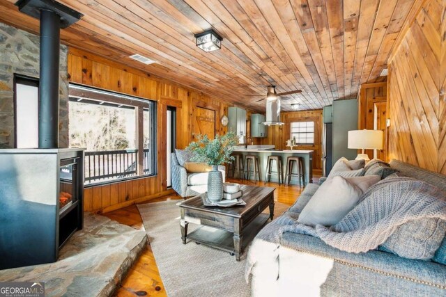 853 Bates Rd, Ellijay, GA 30540 - living room with wood walls, a wood stove, wood ceiling, a ceiling fan, and wood finished floors