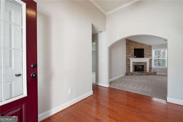 85 Stiles Dr, Dallas, GA 30132 - entryway with crown molding, a stone fireplace, wood finished floors, and arched walkways