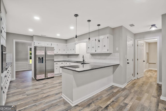 3290 Ebenezer Rd SE, Conyers, GA 30094 - kitchen with appliances with stainless steel finishes, a peninsula, a sink, light wood finished floors, and white cabinets