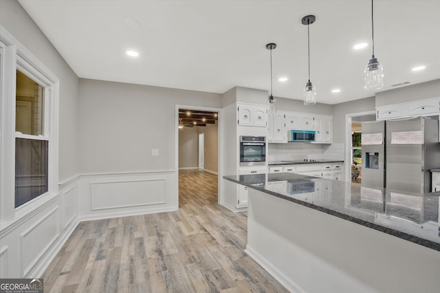 3290 Ebenezer Rd SE, Conyers, GA 30094 - kitchen featuring stainless steel appliances, white cabinetry, light wood-style flooring, dark stone countertops, and a wainscoted wall
