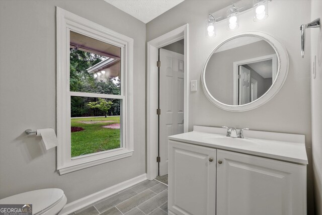 3290 Ebenezer Rd SE, Conyers, GA 30094 - bathroom with vanity, toilet, baseboards, and wood tiled floors