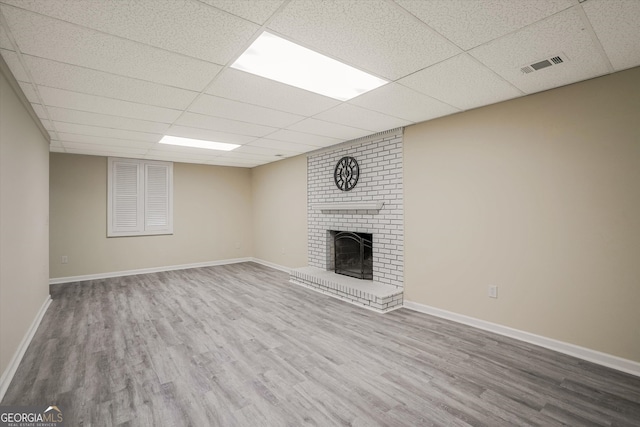 3290 Ebenezer Rd SE, Conyers, GA 30094 - unfurnished living room featuring wood finished floors, a paneled ceiling, a fireplace, and baseboards