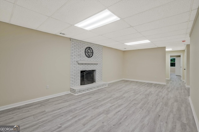 3290 Ebenezer Rd SE, Conyers, GA 30094 - unfurnished living room featuring a drop ceiling, wood finished floors, a brick fireplace, and baseboards