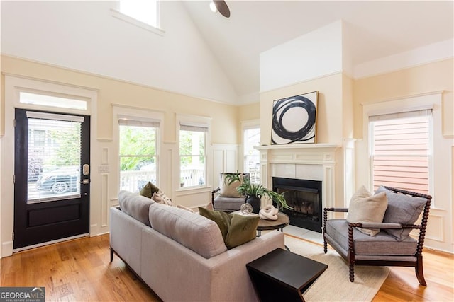 151 Savannah St SE, Atlanta, GA 30316 - living room with high vaulted ceiling, a decorative wall, a tiled fireplace, light wood-style flooring, and wainscoting