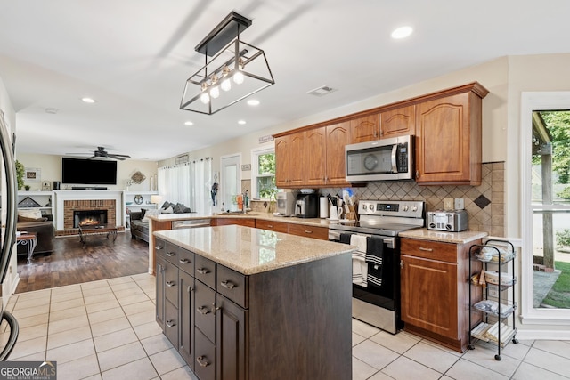 75 Hunters Ct, Dallas, GA 30157 - kitchen featuring appliances with stainless steel finishes, ceiling fan, light stone counters, a brick fireplace, and backsplash