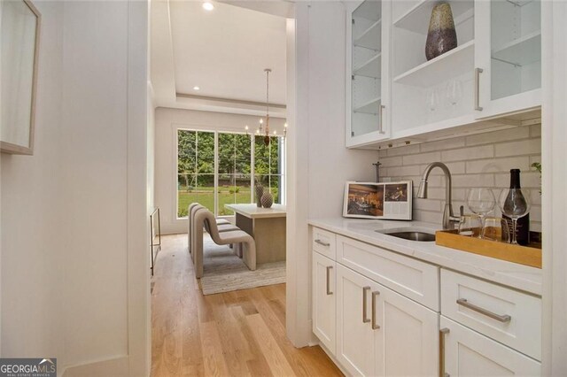 4757 Lake Forrest Dr NW, Atlanta, GA 30342 - bar featuring a sink, light wood-style flooring, decorative backsplash, a chandelier, and recessed lighting