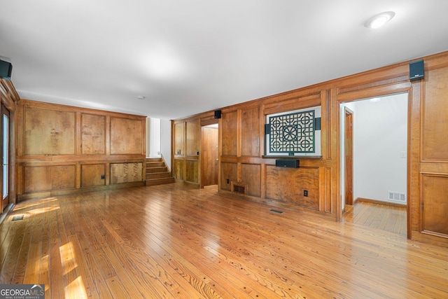 2717 Hearthstone Cir, Marietta, GA 30062 - unfurnished living room featuring light wood finished floors, wooden walls, and stairway