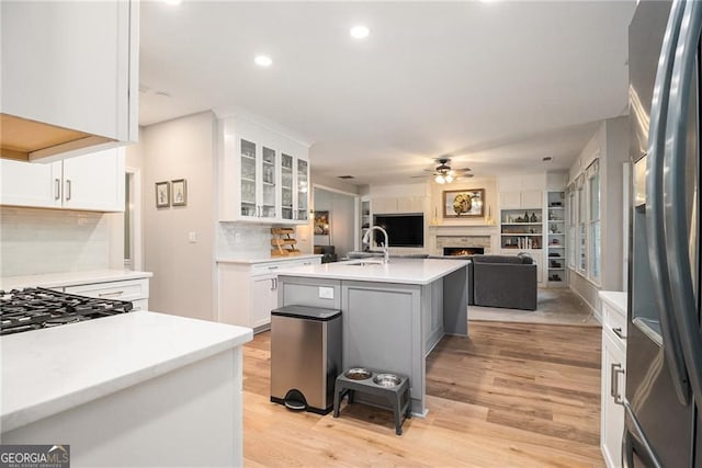 525 Arbor Creek Ct, Roswell, GA 30076 - kitchen featuring stainless steel refrigerator with ice dispenser, a lit fireplace, ceiling fan, tasteful backsplash, and light countertops