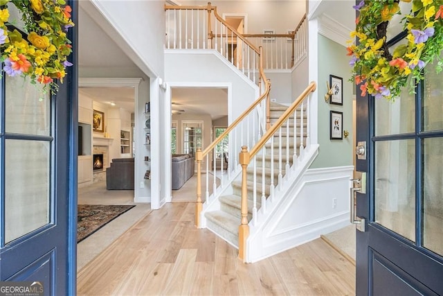 525 Arbor Creek Ct, Roswell, GA 30076 - entrance foyer with stairs, a lit fireplace, light wood-style floors, crown molding, and a decorative wall