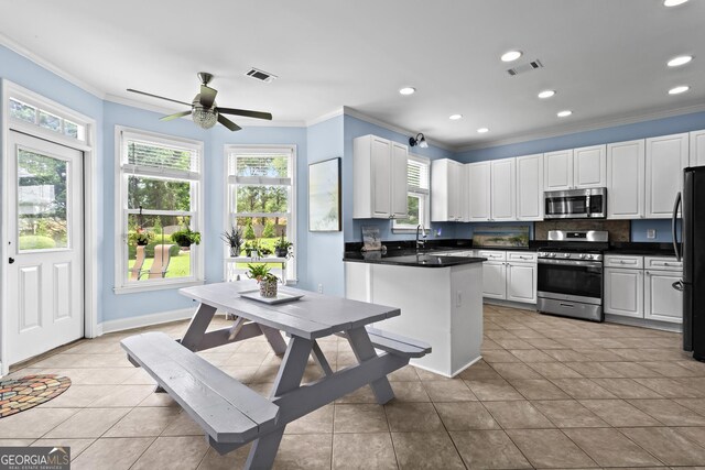4365 Wicklow Ct, Suwanee, GA 30024 - kitchen with stainless steel appliances, ornamental molding, dark countertops, a ceiling fan, and light tile patterned floors