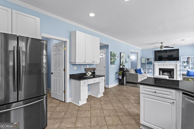 4365 Wicklow Ct, Suwanee, GA 30024 - kitchen featuring stainless steel appliances, a fireplace, a ceiling fan, dark countertops, and white cabinets