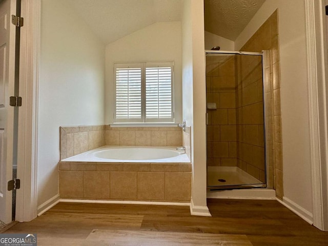 234 Silver Arrow Cir, Austell, GA 30168 - bathroom featuring wood finished floors, a garden tub, a stall shower, lofted ceiling, and baseboards