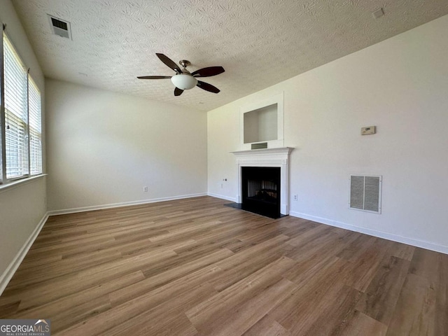 234 Silver Arrow Cir, Austell, GA 30168 - unfurnished living room featuring wood finished floors, a ceiling fan, a textured ceiling, a fireplace with flush hearth, and baseboards