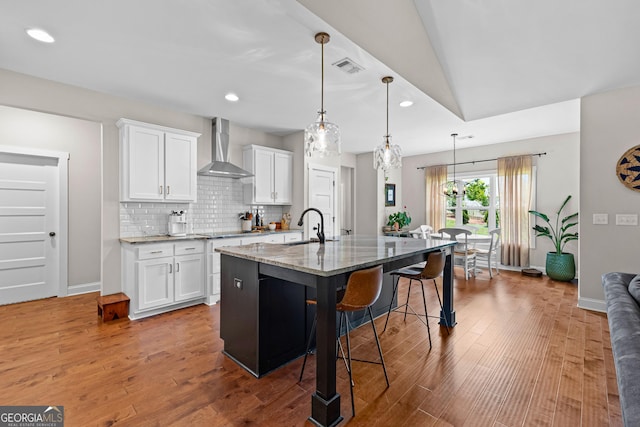 19 E Murphy St, Newnan, GA 30263 - kitchen featuring wall chimney exhaust hood, a kitchen bar, a sink, light stone counters, and wood finished floors