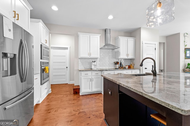 19 E Murphy St, Newnan, GA 30263 - kitchen featuring stainless steel appliances, wall chimney range hood, a sink, light wood-type flooring, and white cabinets