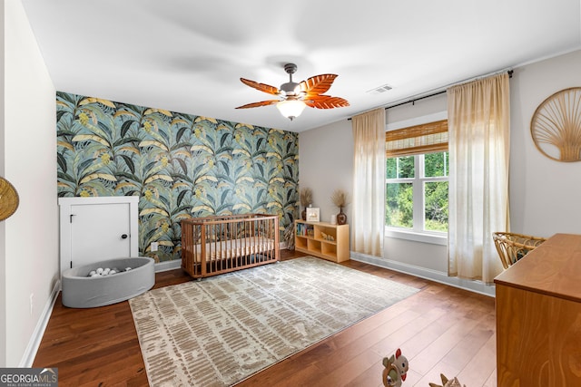 19 E Murphy St, Newnan, GA 30263 - bedroom featuring an accent wall, wallpapered walls, baseboards, wood finished floors, and a crib