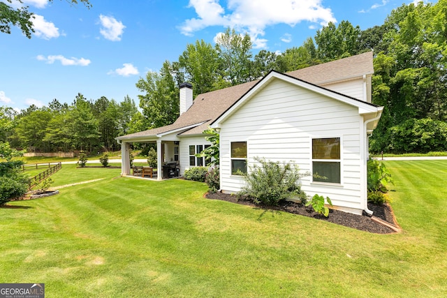 19 E Murphy St, Newnan, GA 30263 - view of side of home with a chimney, a lawn, a shingled roof, and a patio area