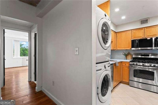 2479 Peachtree Rd NE Unit 305, Atlanta, GA 30305 - kitchen featuring stainless steel appliances, stacked washer and clothes dryer, backsplash, light countertops, and light wood finished floors