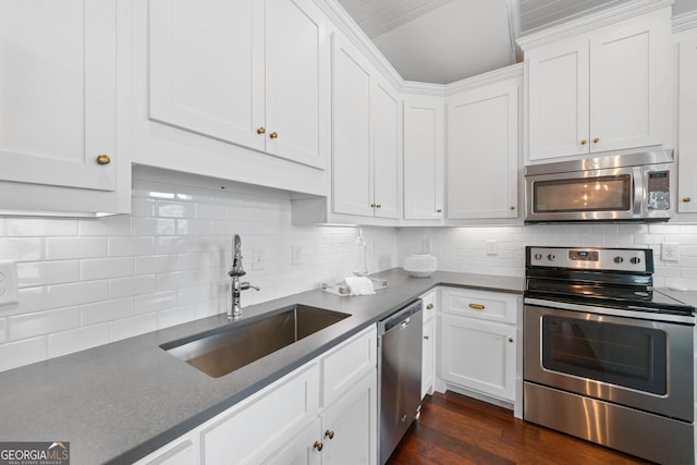 435 New St, Macon, GA 31201 - kitchen with appliances with stainless steel finishes, a sink, dark countertops, white cabinetry, and decorative backsplash