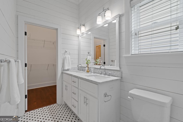 435 New St, Macon, GA 31201 - full bathroom with toilet, wooden walls, double vanity, a walk in closet, and tile patterned floors