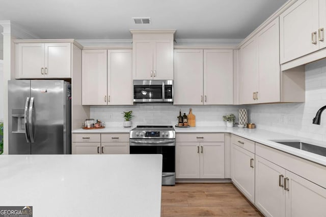 153 Witter Way, Woodstock, GA 30188 - kitchen with stainless steel appliances, light countertops, tasteful backsplash, light wood-type flooring, and ornamental molding