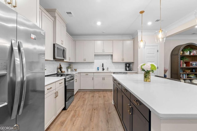 153 Witter Way, Woodstock, GA 30188 - kitchen featuring appliances with stainless steel finishes, light countertops, crown molding, decorative backsplash, and light wood-type flooring
