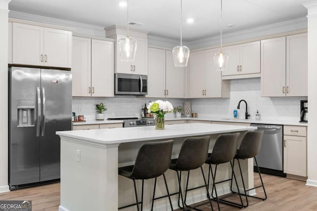 153 Witter Way, Woodstock, GA 30188 - kitchen featuring stainless steel appliances, a center island, light countertops, tasteful backsplash, and light wood-style floors